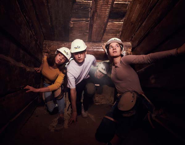Vier Jugendliche kriechen durch einen Bergwerksstollen