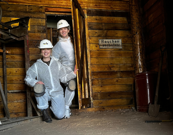 Zwei Junge Frau mit Helm und Schutzanzug erkundet Bergwerksstollen