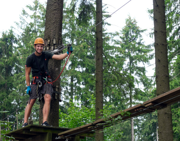 Ein junger Mann im Kletterparkvor einem neuen Element